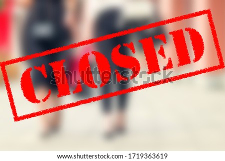 Word CLOSED on background of two young women in the shopping mall. Coronavirus quarantine. Closed shopping mall.