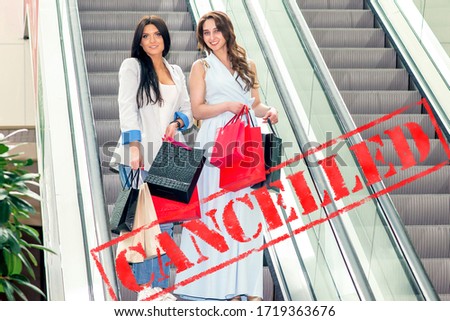 Word CANCELLED on background of two young women in the shopping mall. Coronavirus quarantine. Closed shopping mall.