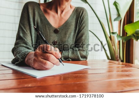 woman signs a document on a wooden table