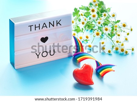 Lightbox with text "Thank you", camomile flowers. Heart, rainbow ribbon, symbols of public support for doctors, nurses, medical stuff fight Covid-19 pneumonia across the globe in many countries.