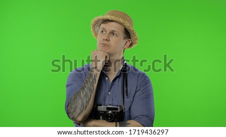 Portrait of man fashion tourist photographer thinking. Handsome man on vacation in blue shirt and hat with retro camera. Place for your logo or text. Chroma key. Green screen