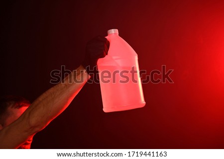 Man in fire holding bottle with water on a red smoky background