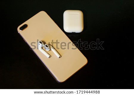 White wireless headphones on a black background. Phone with headphones and a case for charging