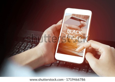 Black Friday shopping app in a mobile phone screen, while smiling woman holds it in the hand