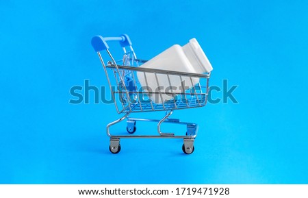 Shopping basket and medical jar with pills for the treatment of colds, flu, and viral diseases. Medical concept of purchasing medical drugs, medications or cosmetics on blue background. Royalty-Free Stock Photo #1719471928