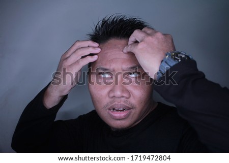 portrait of young Asian man face while dizzy while holding his head, photo concept of best selling Asian male expression