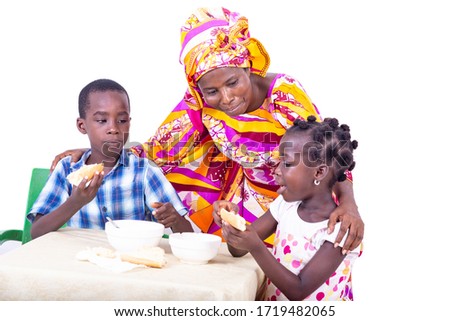 beautiful happy adult mother watching her grandchildren having their breakfast at the table at home.