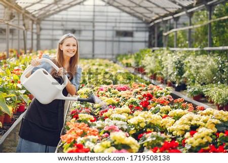 Woman in a greenhouse. Worker pours flowerpoots. Girl in a black apron.