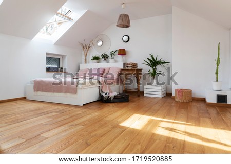 White interior of bedroom with wooden floor and double bed with pink pillows. Bright cozy bedroom in scandinavian style in the attic. Royalty-Free Stock Photo #1719520885