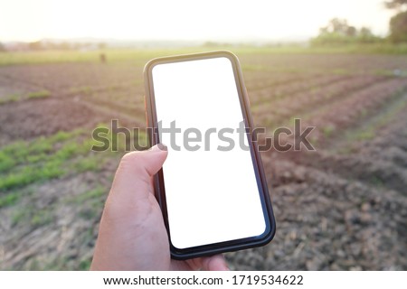 Farmer, The man holding smart phone in the farm with blank copy space screen for your text message or information content. Smart phone with hand in the farm, garden with green mountain view.