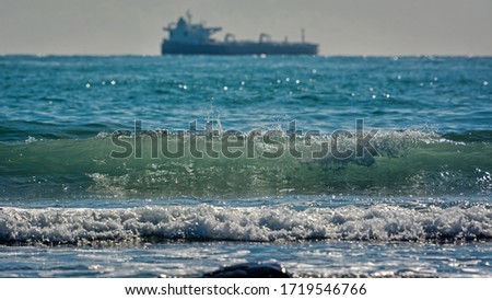 Beachbreak and large laden tanker on horizon