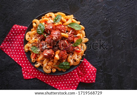 Italian cavatappi Pasta with meatballs in tomato sauce on a black background. The view from the top Royalty-Free Stock Photo #1719568729