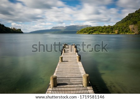 Long exposure of wooden jetty with lake during nice summer day. Lake Tarawera, New Zealand