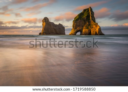 Evening light on Wharariki Beach with its famous rock formations during low tide. New Zealand