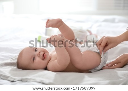 Mother changing her baby's diaper on bed Royalty-Free Stock Photo #1719589099