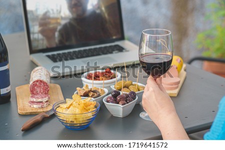 Adult couples clinking online with beer and wine making a quarantine happy hour toast via internet video call. Alcohol and aperitif lifestyle concept. focus on the wineglass.
