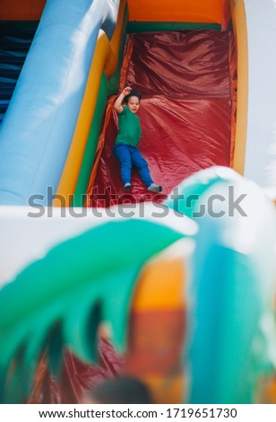 Happy little smiling boy climbing to slide at an amusement park
