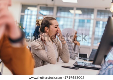Portrait of a tired businesswoman yawning while having a business meeting in the office. Royalty-Free Stock Photo #1719653002