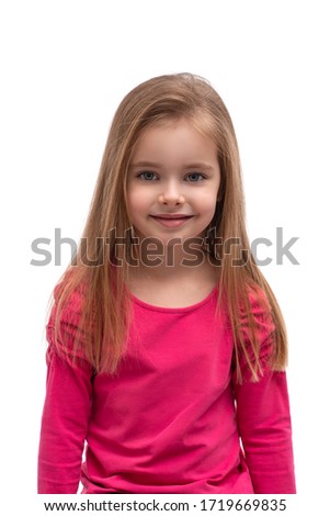 Waist up portrait of a cute blonde smiling little girl with long hair and blue eyes against white background in studio