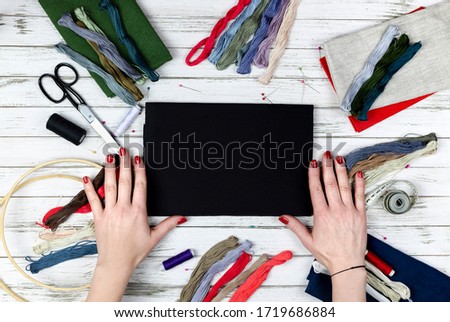 there are quilting, embroidery and sewing tools on the table. patchwork knife, scissors, lined cutting mat, self-locking, threads, measuring tape, floss, hoop. copy space