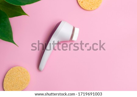 Facial cleansing brush with face sponges on soft pink background. Top view with copy space Royalty-Free Stock Photo #1719691003