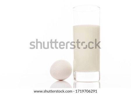Organic milk in a glass and white chicken egg isolated on white background with copyspace