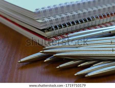 metal ball pens in bulk and notebooks on the table Royalty-Free Stock Photo #1719710179