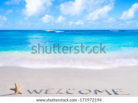 Sign"Welcome" with starfish on the sandy beach by the ocean