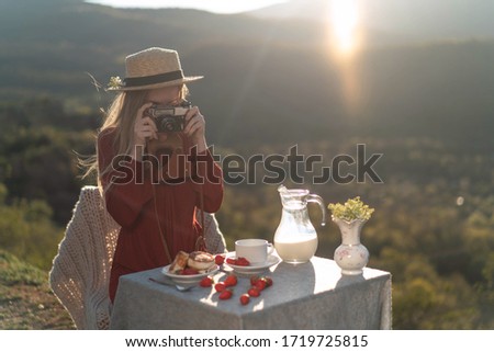 A girl outdoors takes pictures of breakfast, milk, cheesecakes. Eco farm.