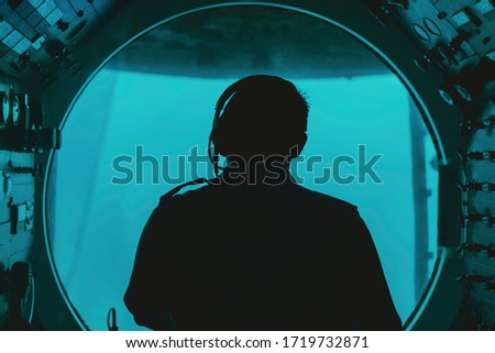 silhouette of a pilot in submarine cockpit under water Royalty-Free Stock Photo #1719732871