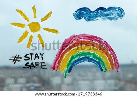 painting stay safe hashtag at a wet glass with sun and rainbow. selfisolation during quarantine Covid-19 Royalty-Free Stock Photo #1719738346