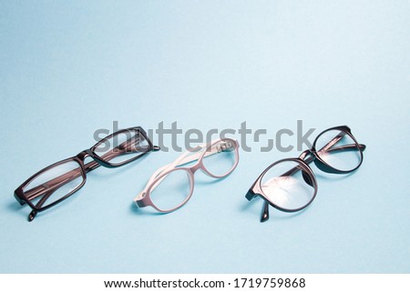 several pairs of different glasses for vision correction on a blue background; copy space, children's glasses and small rivers for adults