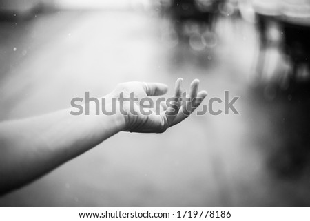 Woman holds hand and catches raindrops black and white