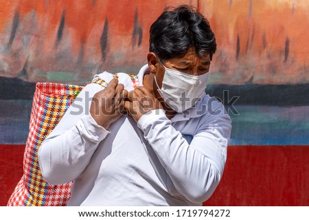 Man in respiratory mask during coronavirus pandemic in market with bag of food in Cusco, Peru in Latin South America. Epidemic of coronavirus covid-19