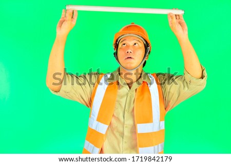 Foreman wearing fluorescent lamp on over green screen background.