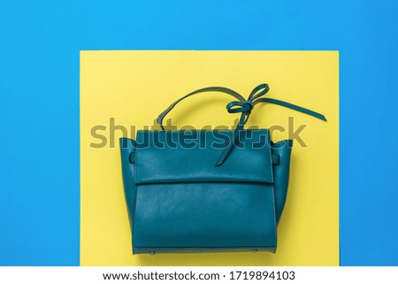 Leather women's bag in turquoise color on a yellow and blue background. The view from the top. Flat lay.