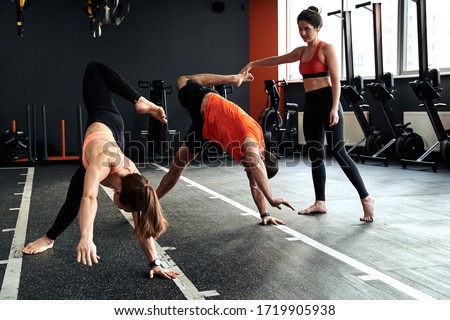 Group of young adult athletes working out at animal flow style, making scorpio position, training together with personal coach in sport center Royalty-Free Stock Photo #1719905938