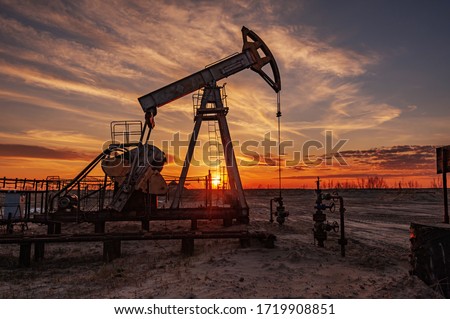 Oil pump rig. Oil and gas production. Oilfield site. Pump Jack are running. Drilling derricks for fossil fuels output and crude oil production. War on oil prices. Global coronavirus COVID 19 crisis. Royalty-Free Stock Photo #1719908851