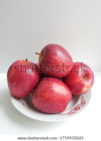 Red apples on a porcelain plate.
