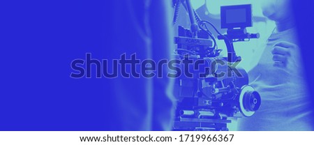 Colorful images of behind the scenes shooting production crew team and hd video camera equipment in studio which includes tripod, soft box light, monitors, lens for making film or movie or broadcast