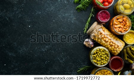 Food stocks in glass jars. Pickled vegetables. On a black background. Top view.