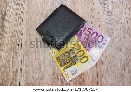 500, 200 euros in a black men's wallet on a wooden background. View from above.