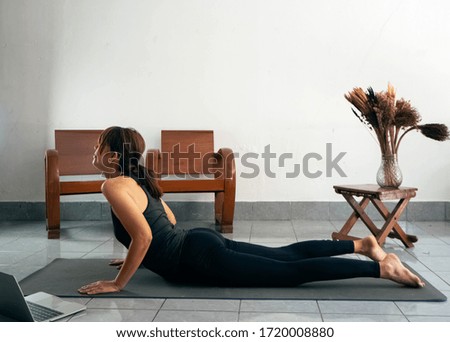Woman wearing exercise suit,bend back body up,strteching body on yoga mat,at home
