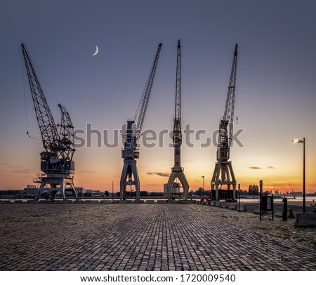 A row of 4 old harbor cranes in the city of Antwerp. Royalty-Free Stock Photo #1720009540