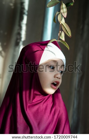 Portrait of a happy muslim toddler girl with hijab. Natural light, selective focus.