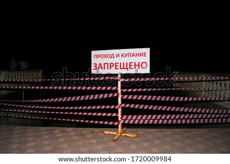 Closed path, no passage. Banner with the inscription - translated into Russian: passage and bathing is prohibited. The path to the sea is enclosed by a barrier tape.