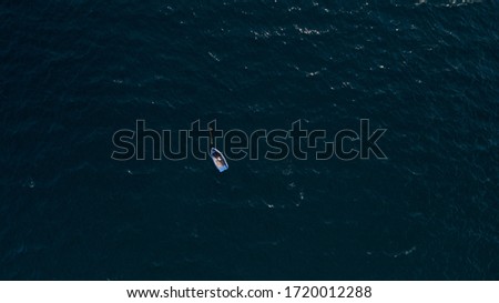 This stock photo features a small row boat sitting on the rough seas.