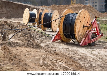 Several wooden coils with power cable laid in trench. Concept of electricity supply for construction projects.
