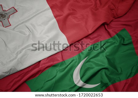 waving colorful flag of maldives and national flag of malta. macro