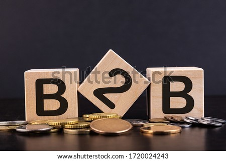 Cubes with word B2B and stacked coins on wooden surface